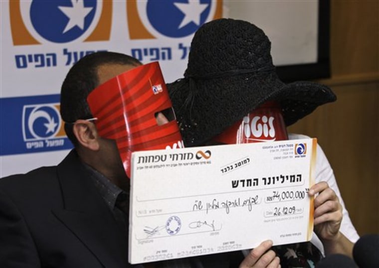 An Israeli couple conceal their identity while claiming their lottery prize on Tuesday. The Hebrew writing on their masks reads "Lotto", and on the check "The new millionaire. Seventy four million NIS" (about $20 million). 